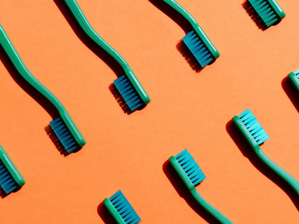 Toothbrushes on orange background dentist in Washington MI